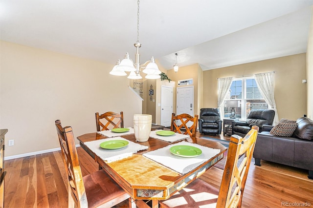 dining area featuring lofted ceiling, light wood-style floors, baseboards, and a notable chandelier