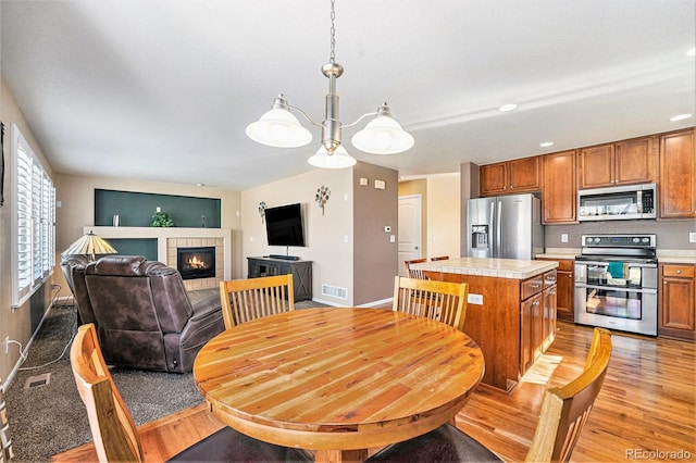 dining space featuring light wood finished floors, a fireplace, and visible vents