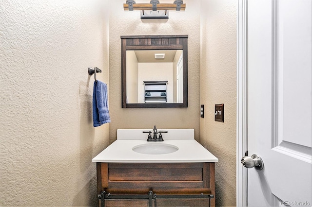 bathroom with a textured wall and vanity