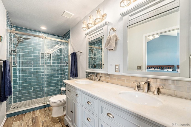 full bathroom with wood finish floors, visible vents, a sink, and a shower stall