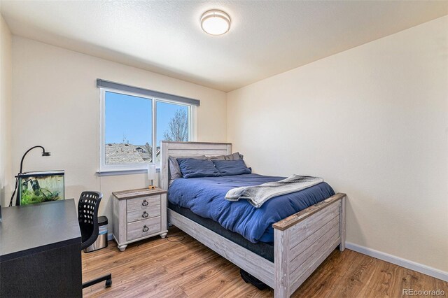 bedroom with baseboards and wood finished floors