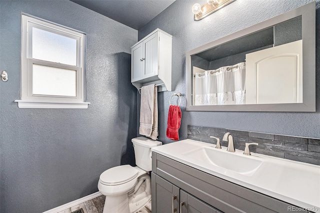 full bath featuring a textured wall, vanity, toilet, and wood finished floors