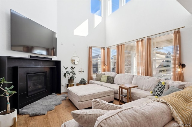 12264 Olive Way, Thornton, CO 80602 - living area featuring plenty of natural light, a towering ceiling, wood finished floors, and a glass covered fireplace