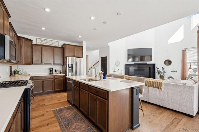 12264 Olive Way, Thornton, CO 80602 - kitchen featuring stainless steel appliances, open floor plan, decorative backsplash, light countertops, and light wood finished floors
