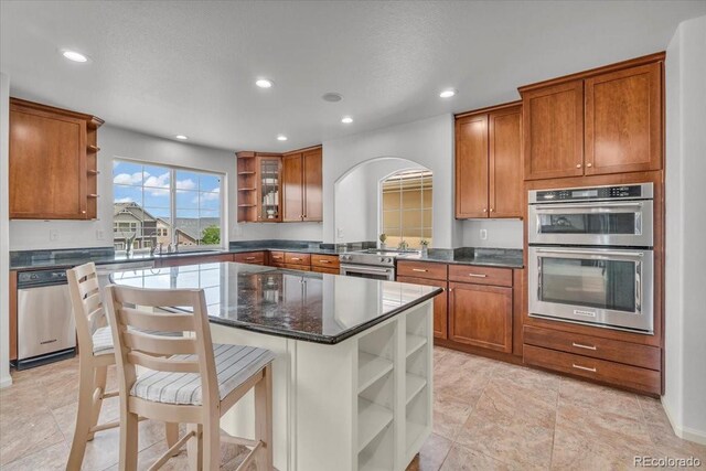1385 Candleglow St, Castle Rock, CO 80109 - kitchen featuring open shelves, appliances with stainless steel finishes, brown cabinets, recessed lighting, and a center island