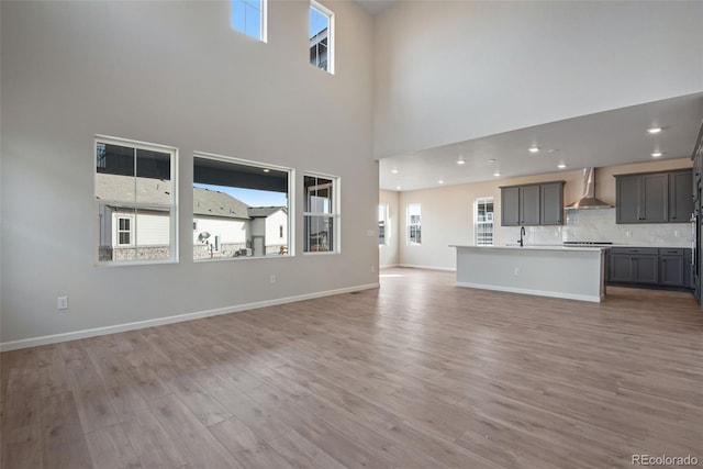 unfurnished living room featuring light wood finished floors, recessed lighting, and baseboards