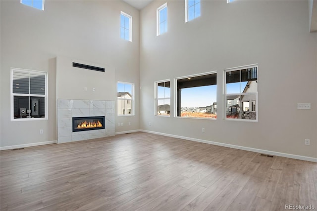 unfurnished living room featuring a tiled fireplace, wood finished floors, and baseboards