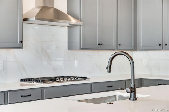 kitchen with wall chimney range hood, tasteful backsplash, gray cabinets, and light countertops