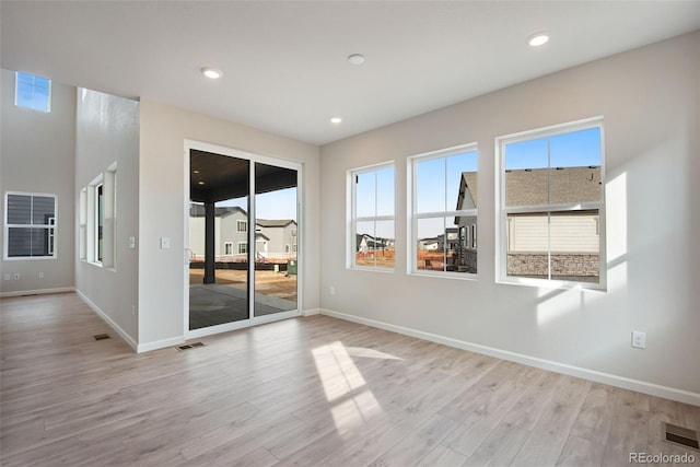 unfurnished room with light wood-style flooring, visible vents, and baseboards