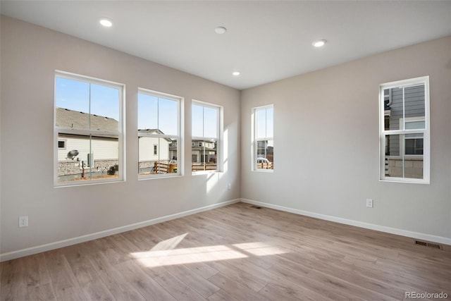 spare room with recessed lighting, plenty of natural light, light wood-style flooring, and baseboards