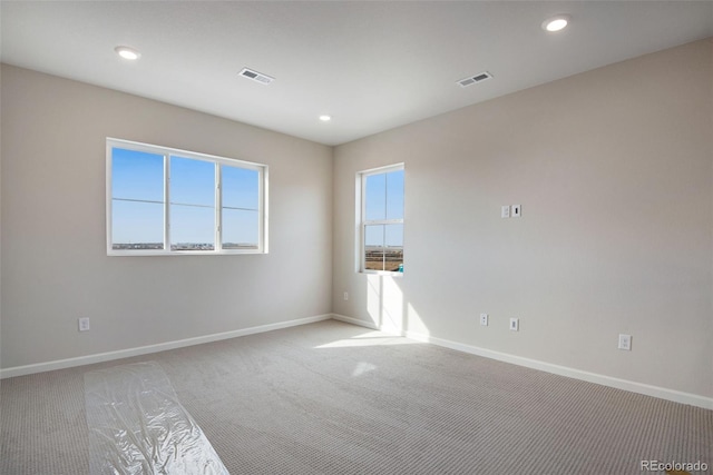 empty room with recessed lighting, visible vents, light carpet, and baseboards