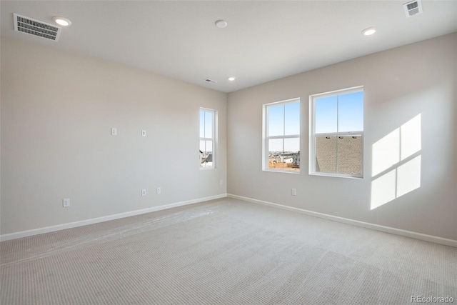 empty room featuring baseboards, visible vents, and light colored carpet