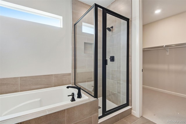 full bathroom with a walk in closet, tile patterned floors, a shower stall, and a bath