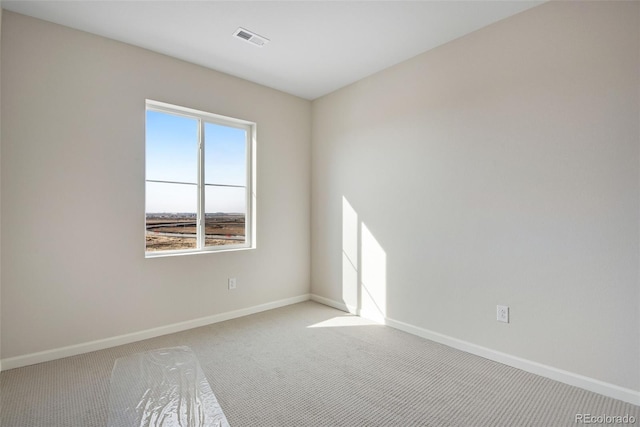 empty room with carpet, visible vents, and baseboards