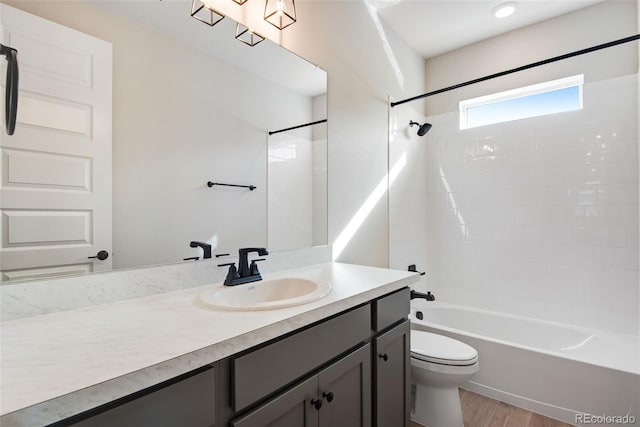 bathroom with wood finished floors, vanity, toilet, and shower / bathtub combination