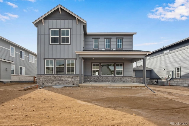 rear view of property with central AC, stone siding, and board and batten siding