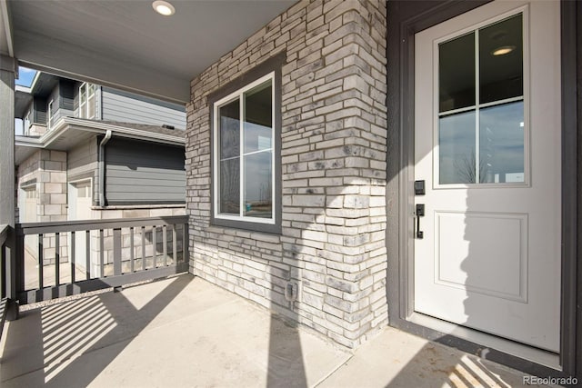 property entrance featuring a porch and brick siding