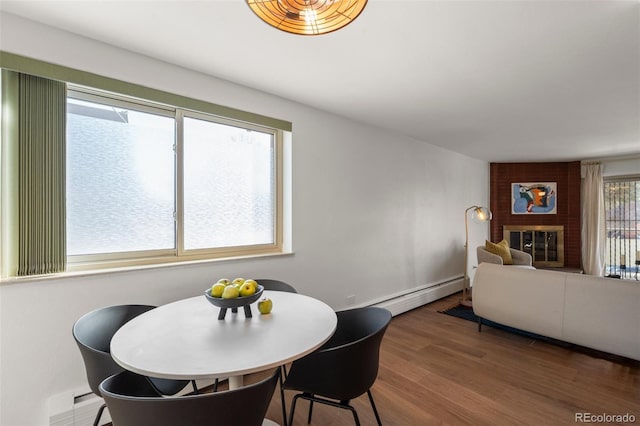 dining area with baseboard heating, hardwood / wood-style floors, and a fireplace