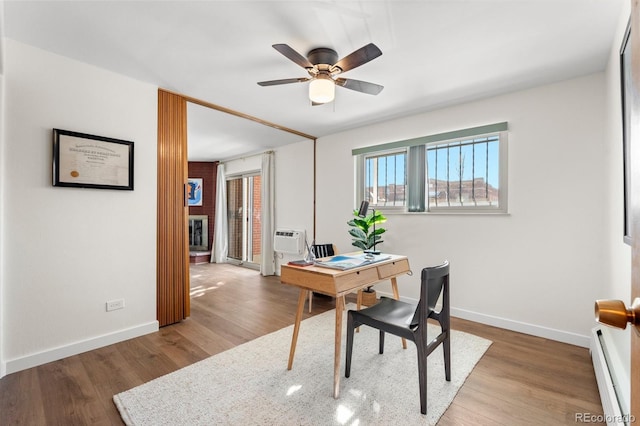 home office featuring a baseboard radiator, a wall mounted air conditioner, ceiling fan, and wood-type flooring