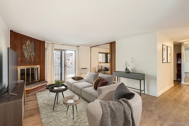 living room featuring baseboards, wood finished floors, and a brick fireplace