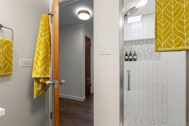 bathroom with baseboards, wood finished floors, and a stall shower