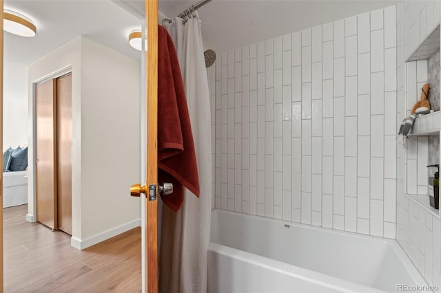 full bathroom with baseboards, wood finished floors, and shower / tub combo with curtain