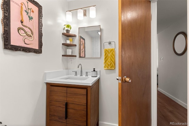 bathroom featuring baseboards, wood finished floors, and vanity