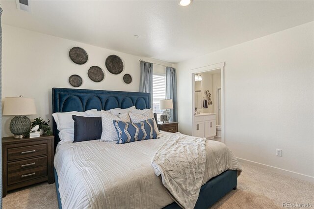 bedroom with ensuite bathroom and light colored carpet