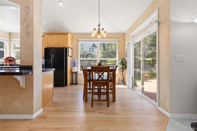 dining area featuring a chandelier, light wood finished floors, a textured wall, baseboards, and vaulted ceiling
