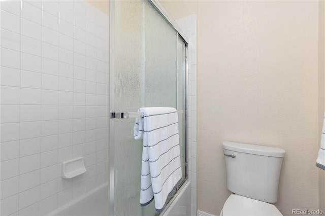 bathroom featuring toilet and combined bath / shower with glass door