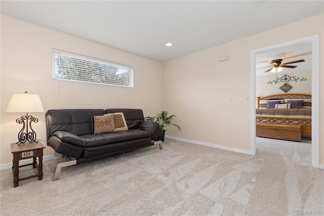 living area featuring carpet, baseboards, and a ceiling fan