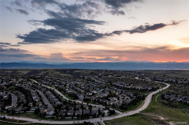 aerial view of property and surrounding area featuring a mountain backdrop and nearby suburban area