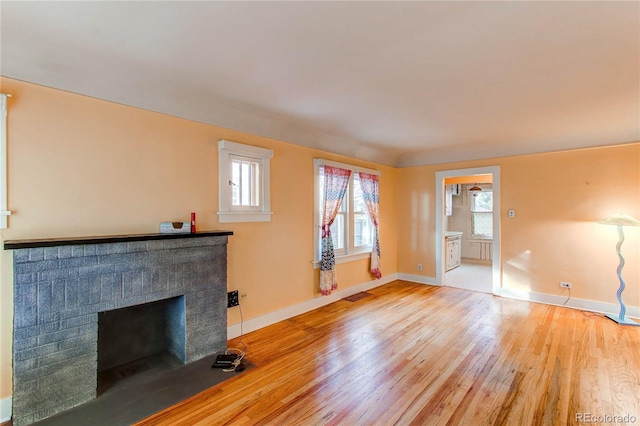 unfurnished living room featuring a brick fireplace and light hardwood / wood-style flooring