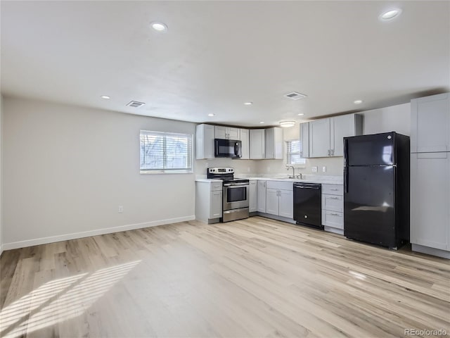 kitchen featuring visible vents, a sink, plenty of natural light, and black appliances