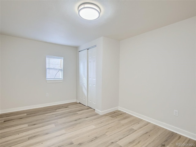 unfurnished bedroom featuring a closet, baseboards, and light wood-type flooring