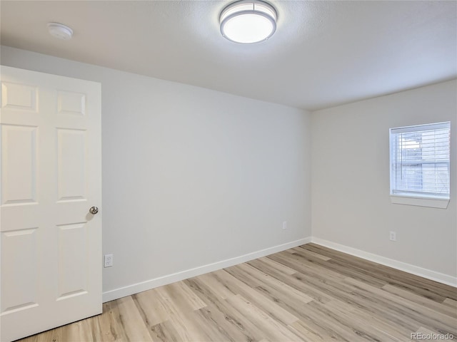empty room featuring baseboards and light wood-style flooring
