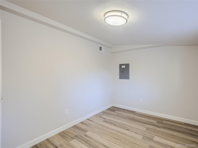 unfurnished room featuring visible vents, light wood finished floors, baseboards, and electric panel