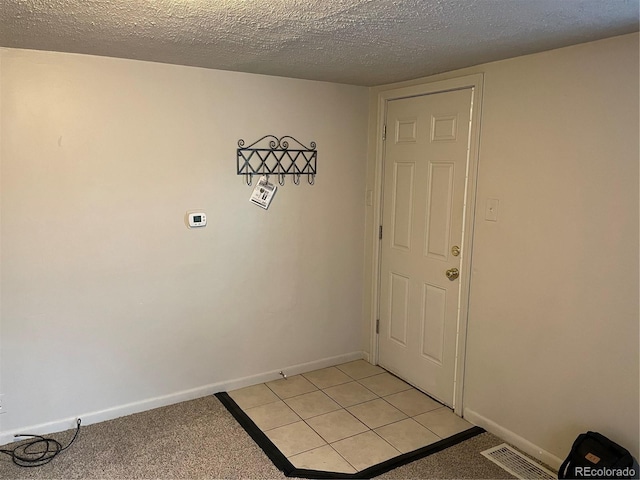 entryway with baseboards, a textured ceiling, and visible vents