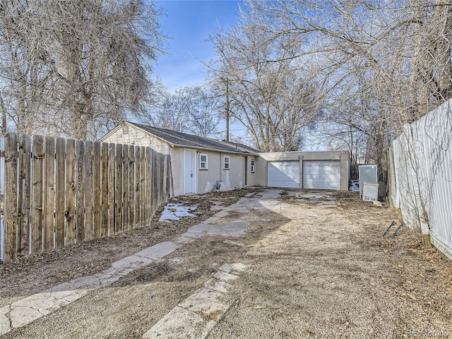 view of side of home featuring an attached garage, fence, driveway, and stucco siding