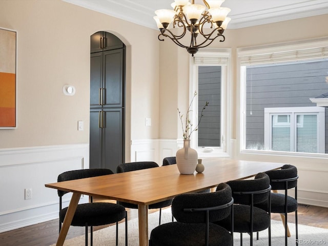 8425 Green Island Cir, Lone Tree, CO 80124 - dining space featuring arched walkways, ornamental molding, a chandelier, wood finished floors, and a wainscoted wall