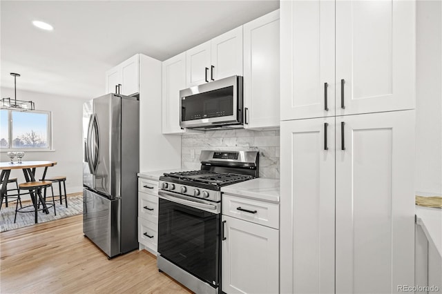 kitchen featuring white cabinetry, decorative backsplash, light hardwood / wood-style flooring, and stainless steel appliances