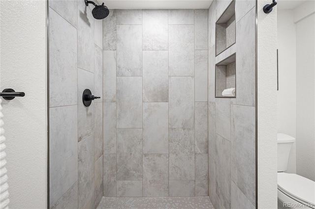 bathroom with toilet and tiled shower