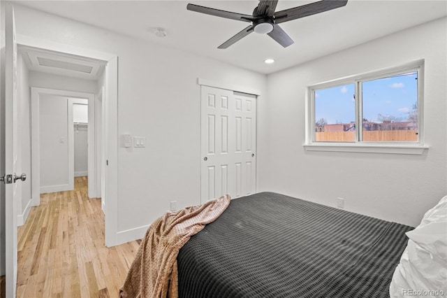 bedroom with ceiling fan, light hardwood / wood-style floors, and a closet