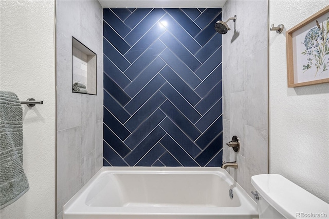 bathroom featuring toilet and tiled shower / bath