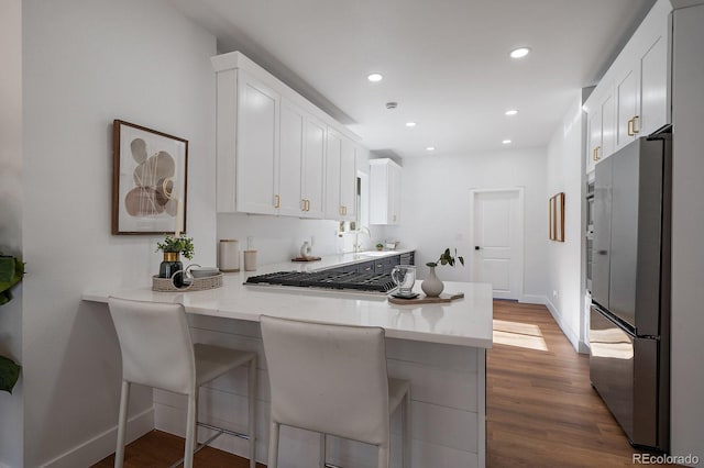 kitchen featuring appliances with stainless steel finishes, white cabinets, a kitchen bar, and kitchen peninsula