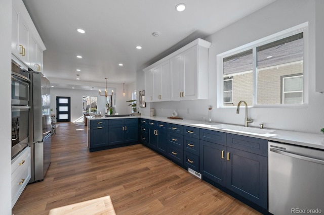 kitchen with appliances with stainless steel finishes, kitchen peninsula, sink, and white cabinets