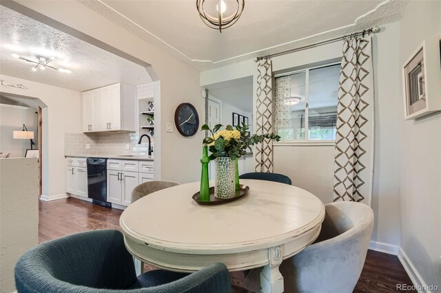 dining area featuring dark wood-type flooring, sink, and a textured ceiling