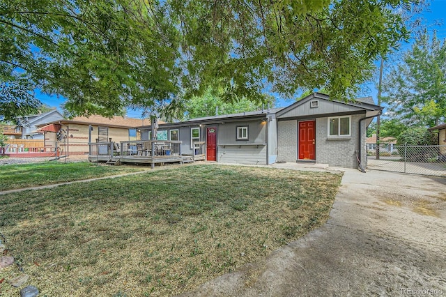 ranch-style home featuring a front yard and a wooden deck