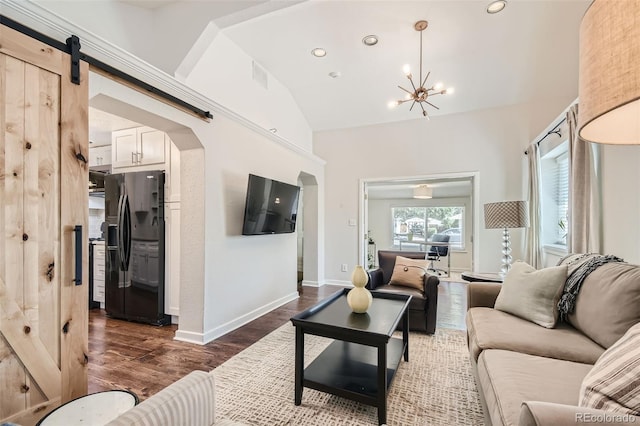 living room with dark wood-type flooring, lofted ceiling, an inviting chandelier, and a barn door