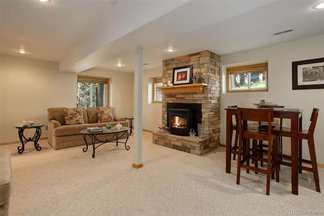 living area featuring baseboards, visible vents, a stone fireplace, and carpet